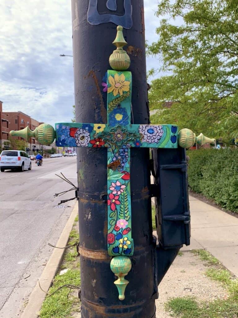 a photo of a cross, turquoise with flowers on it, tied to a telephone pole in Chicago, IL.